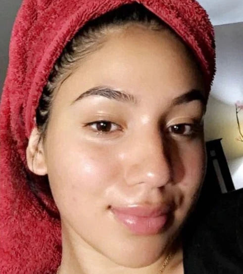 A person with a towel wrapped around their head, smiling at the camera.